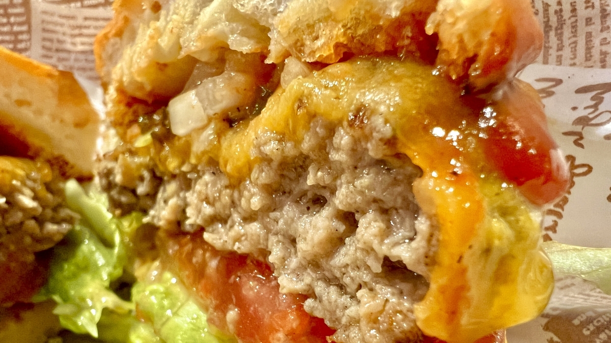 厚いパティととろけるチーズが食欲をそそるバーガーの断面アップ
