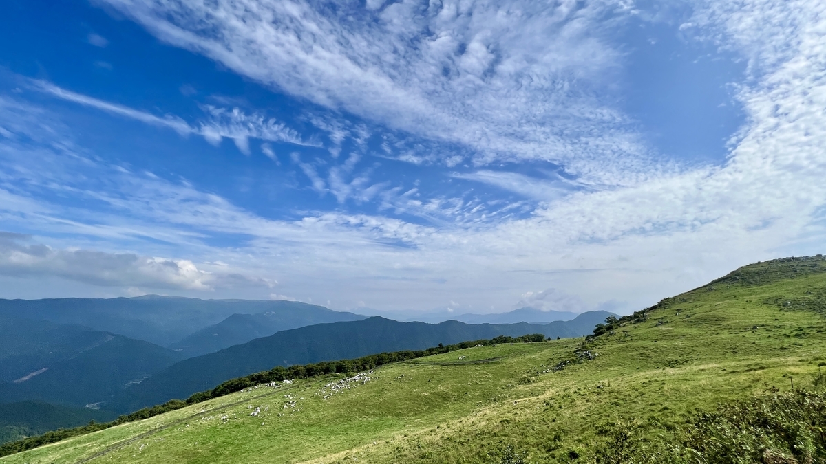 青空と雲が広がる四国カルストの高原風景と遠くの山々