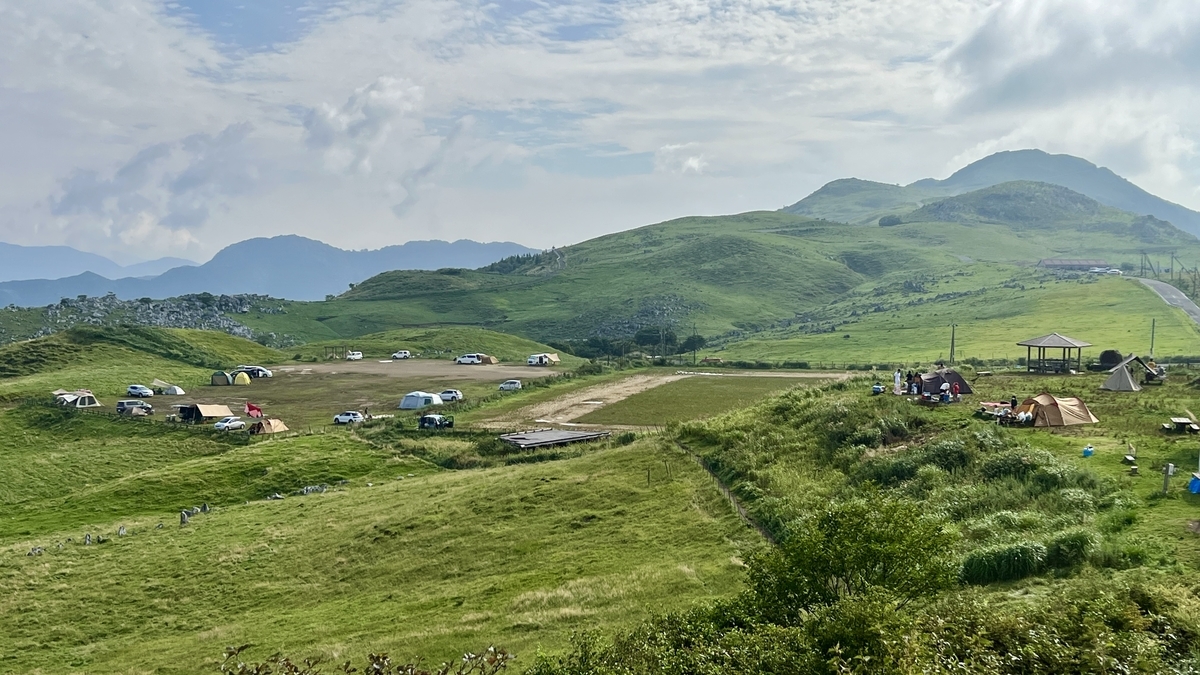 遠くの山々と草原に点在するテントが映る姫鶴平キャンプ場の全景