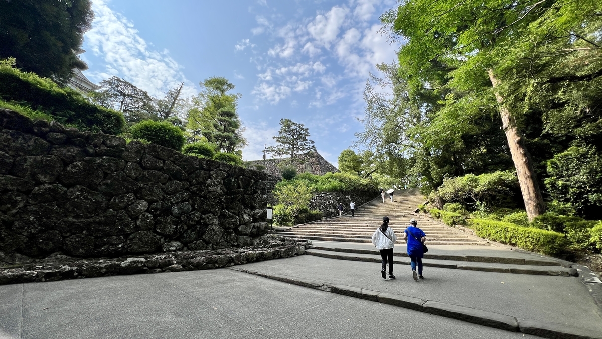 石段の先に高知城天守が見えてくる構図。石垣と緑に囲まれた道