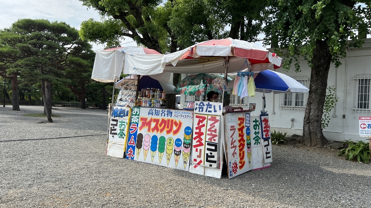 カラフルな看板で装飾された「アイスクリン」販売の移動屋台。白いパラソル付き