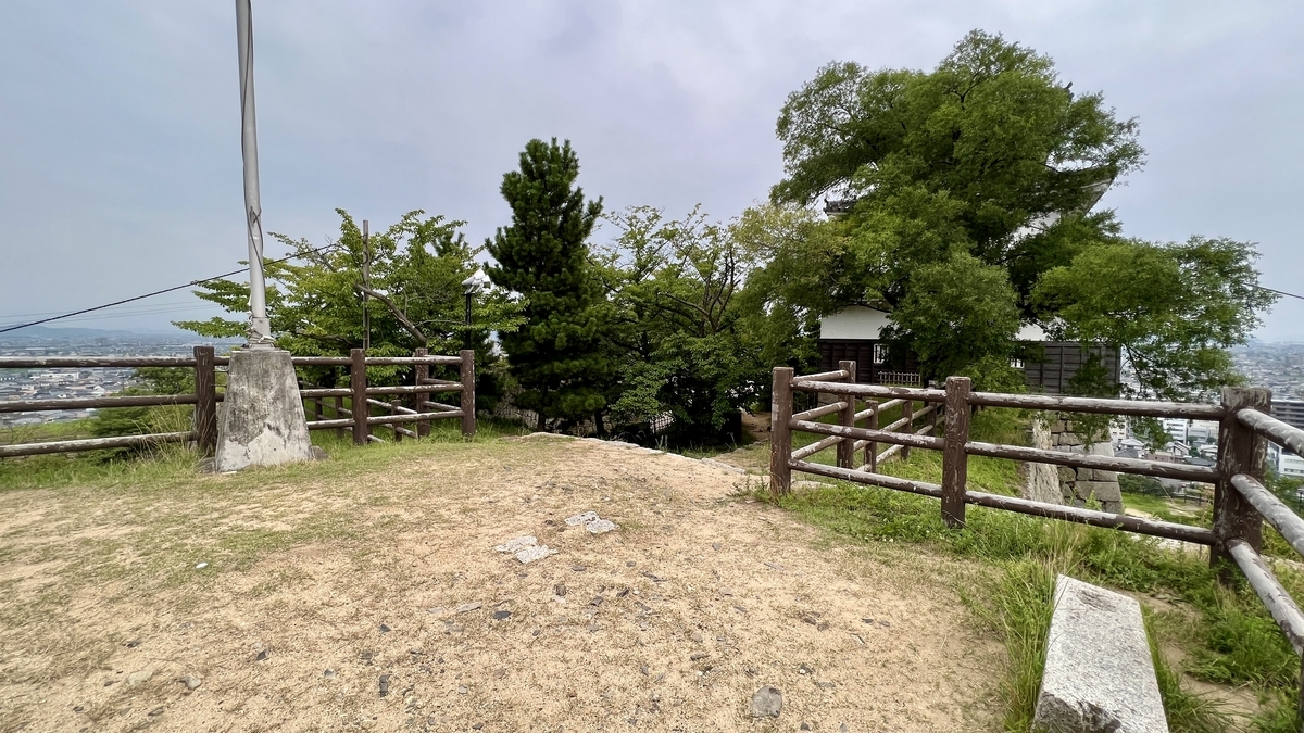 天守裏の展望エリア。案内標柱と木々の向こうに広がる市街地