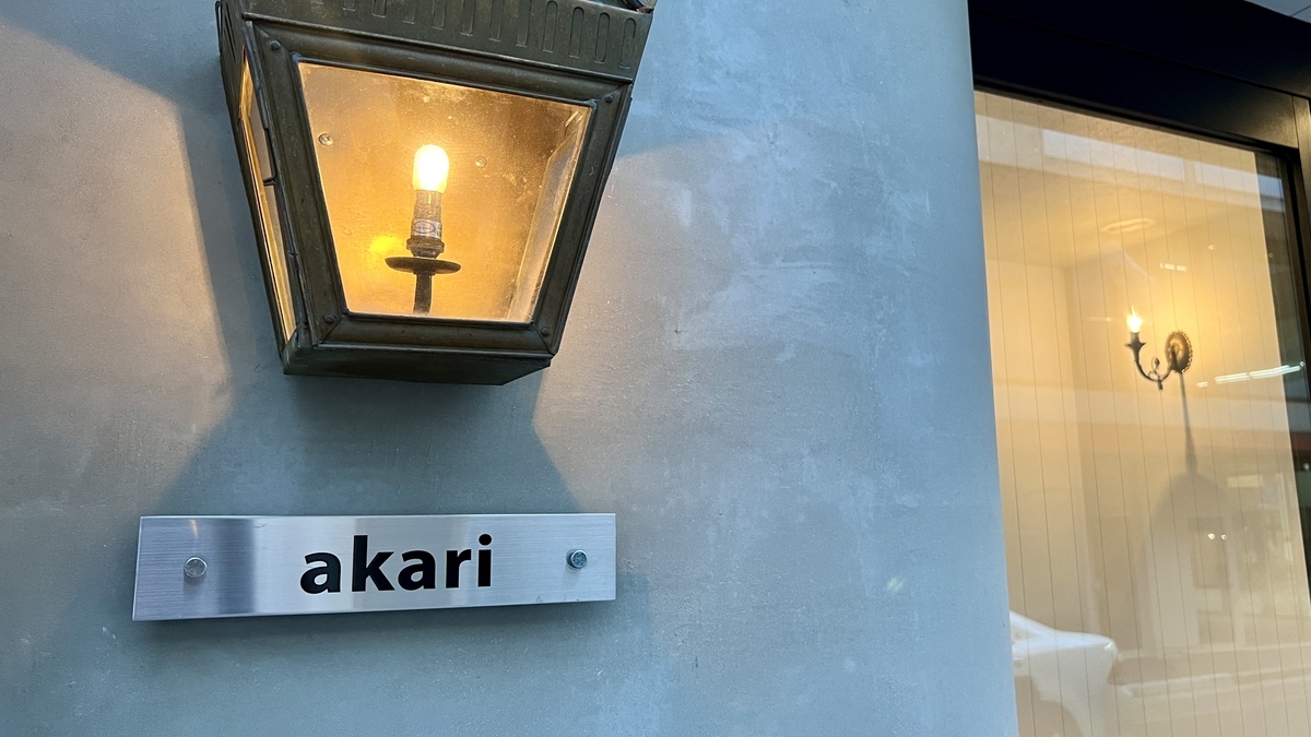 灯りに照らされたakariの店名ロゴと外壁