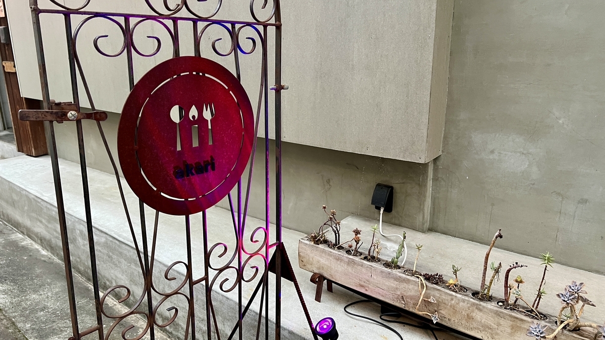 店先に設置された装飾付きの赤いロゴ入りゲートと看板