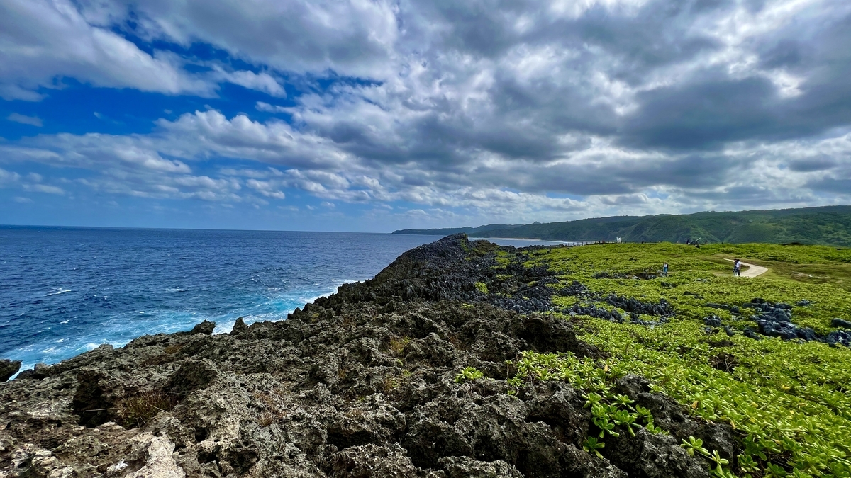 岩場と青い海に緑の草原が広がる辺戸岬の景観