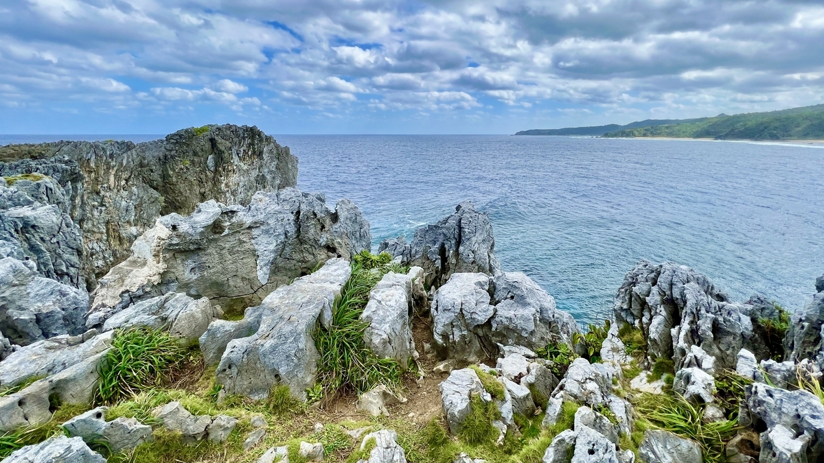 岩場の間から見える青い海と切り立った岬の風景