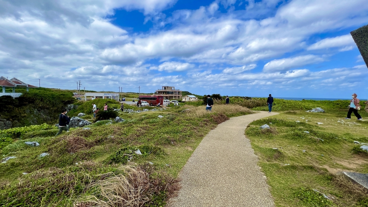 駐車場へ続く遊歩道を歩く人々と広い空