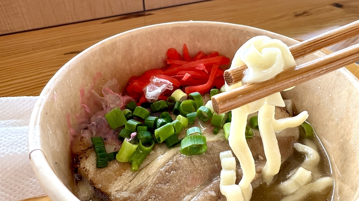 器に盛られた沖縄そばを箸で持ち上げる様子