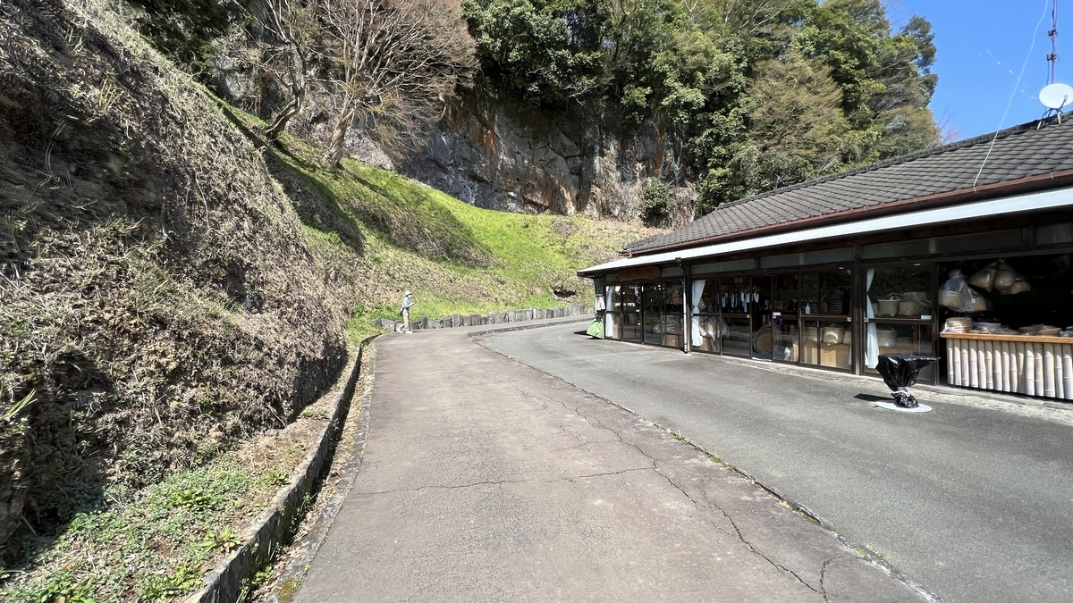 岩山沿いに続く舗装路と土産物店の建物