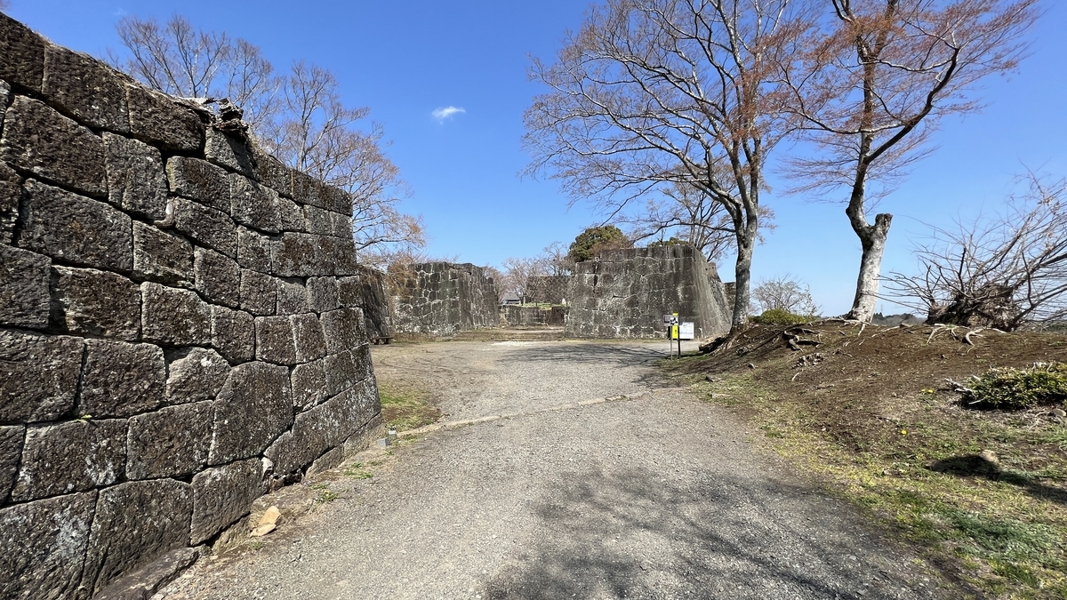 石垣に囲まれた曲がり通路と開けた広場