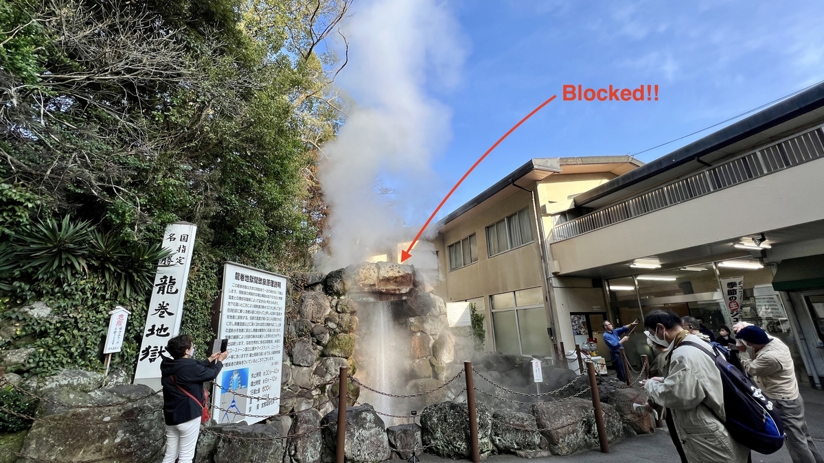 噴出口を岩で塞いだ龍巻地獄の間欠泉と見学する観光客