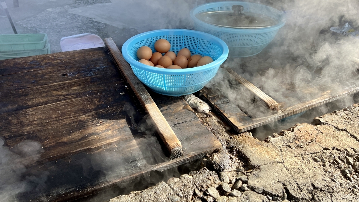 温泉の蒸気で茹でる卵が青いザルに入れられた地獄蒸し釜