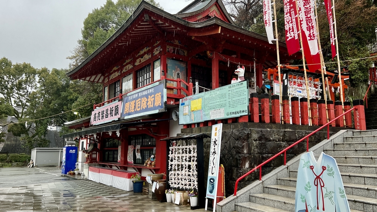 神楽殿と社務所の朱色の建物と石段脇の絵馬掛け