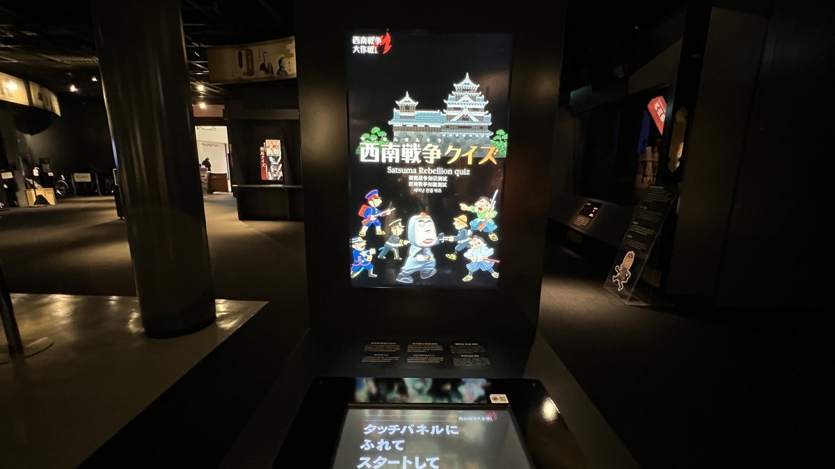 西南戦争クイズのゲーム筐体とタッチパネルが並ぶ展示室