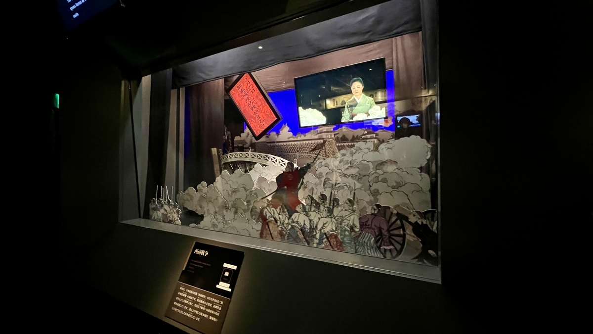 西南戦争の紙芝居風の切り絵展示と背後の映像スクリーン