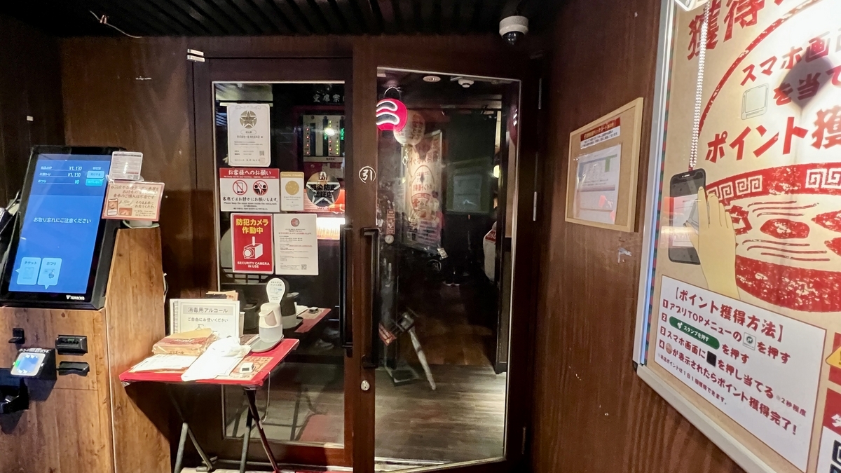 券売機横の受付テーブルと奥へ続く入口ドアの店内導線