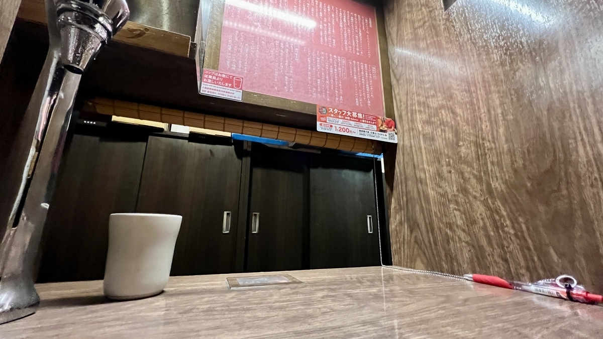 仕切りのある味集中カウンター席のテーブルと注文メニュー掲示