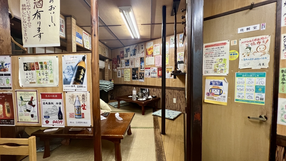 壁に張り紙が並ぶ座敷席と低いテーブルがある奥の座敷