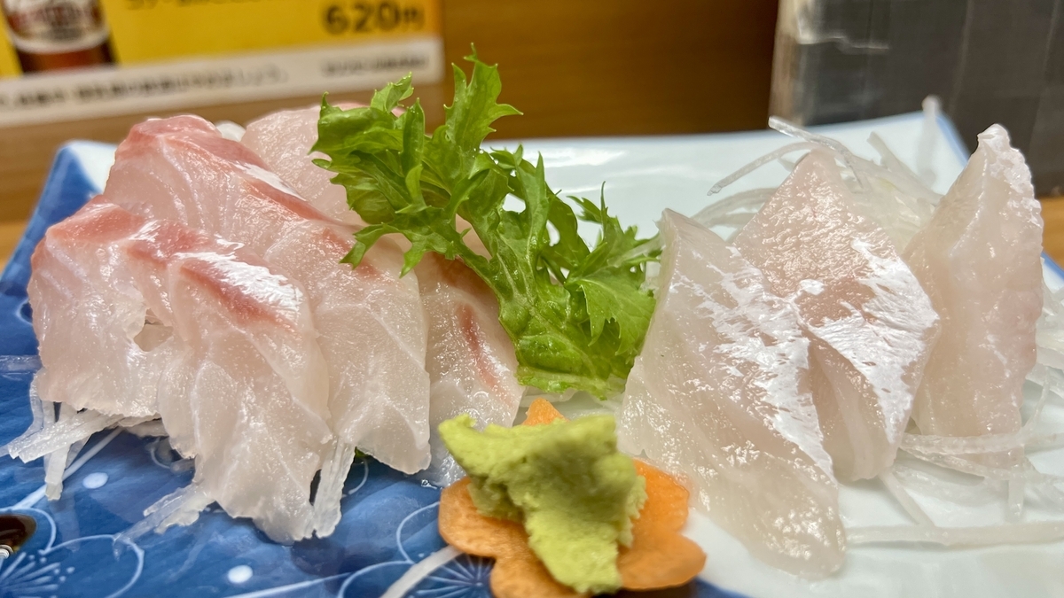 白身魚の刺身が盛られた青い角皿とわさびと青じそ