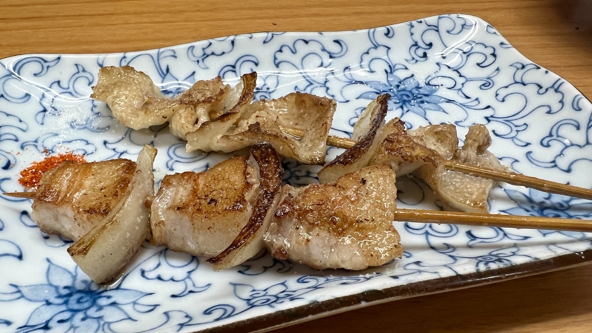 豚バラと皮の串焼きに七味が添えられた青い模様の角皿