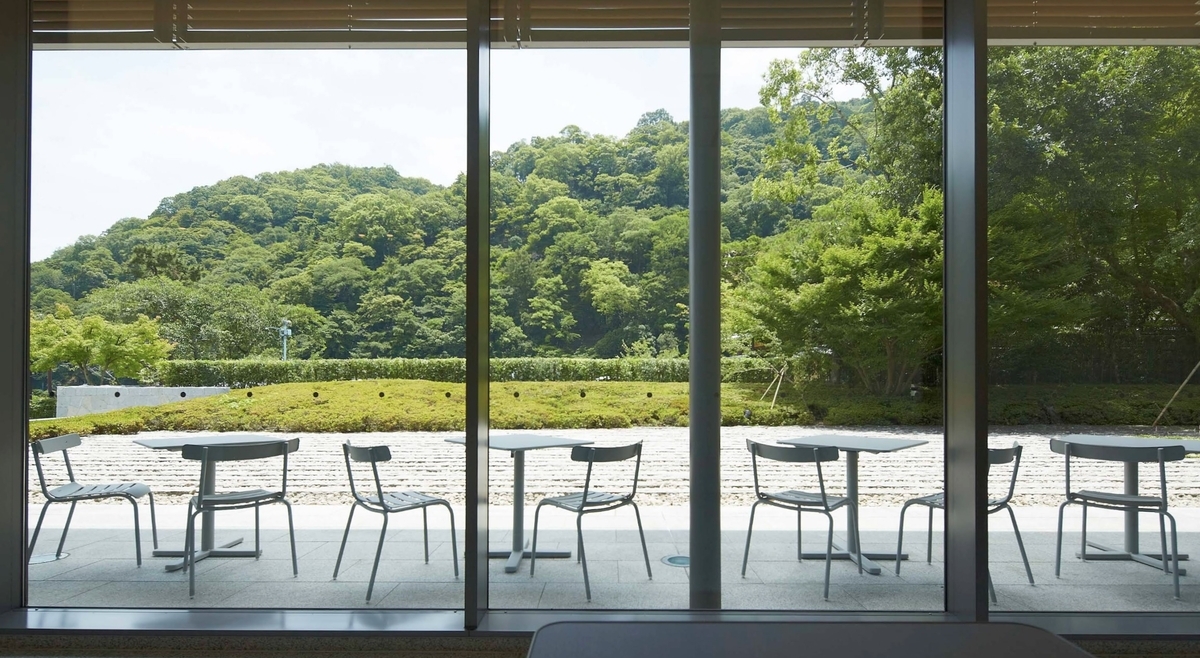 嵐山OMOKAGEテラスのガラス越しに見える屋外席と緑豊かな山並み