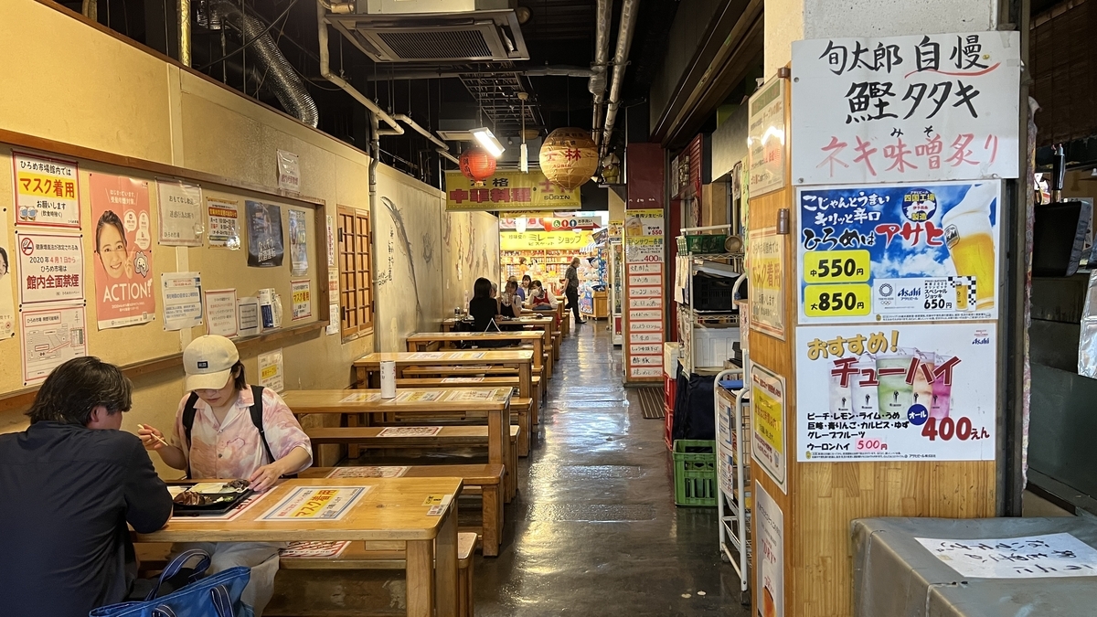 ひろめ市場の共用テーブル席。壁沿いに掲示されたメニューが見える通路