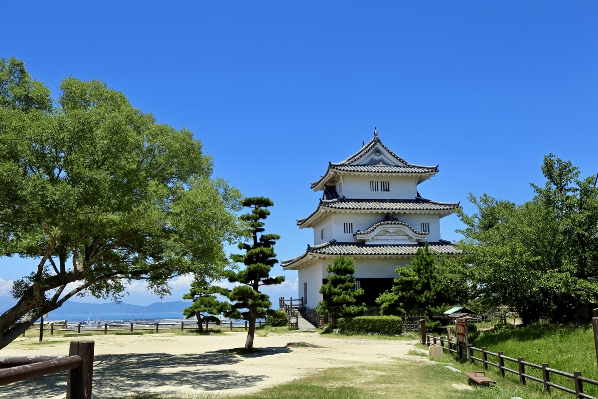 緑に囲まれた丸亀城の天守。青空に映える三層の構造