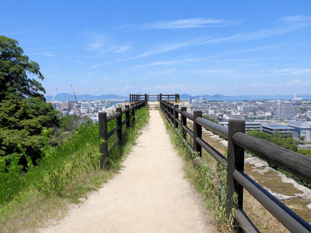 展望台として整備された丸亀城三の丸広場の石垣上の遊歩道。遠くに海と街並みを望む