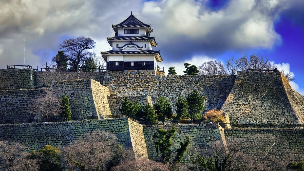 石垣の上に建つ丸亀城の天守。青空と緑に囲まれた威風堂々とした外観