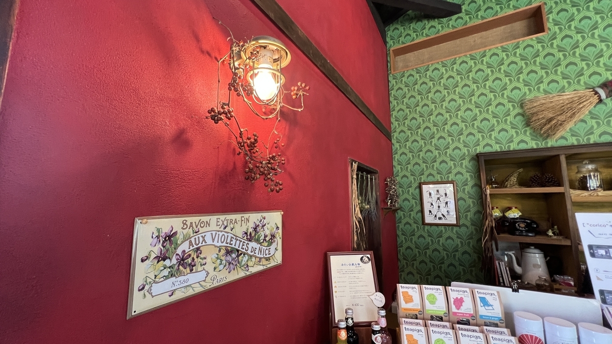 ロケセット店内 赤い壁の照明と飾り棚 ポストカードや小物