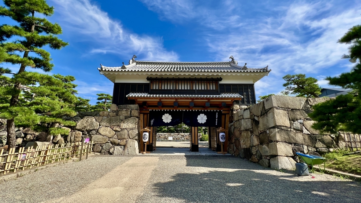 石垣に囲まれた参道から見た桜御門 櫓門越しに広がる松の緑と青空
