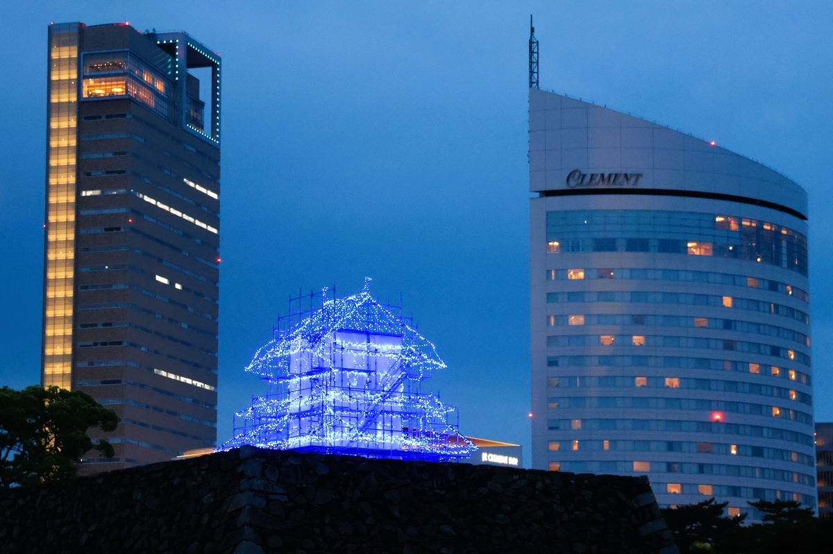 現代ビル群を背景にライトアップされた仮想天守の演出 高松城の天守台から夜空へ浮かび上がる天守の光