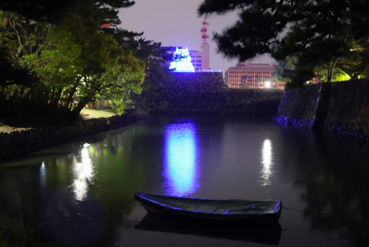 堀に映る青い光と夜の静寂に浮かぶ仮想天守のライトアップ 舟とともに幻想的な水辺の風景