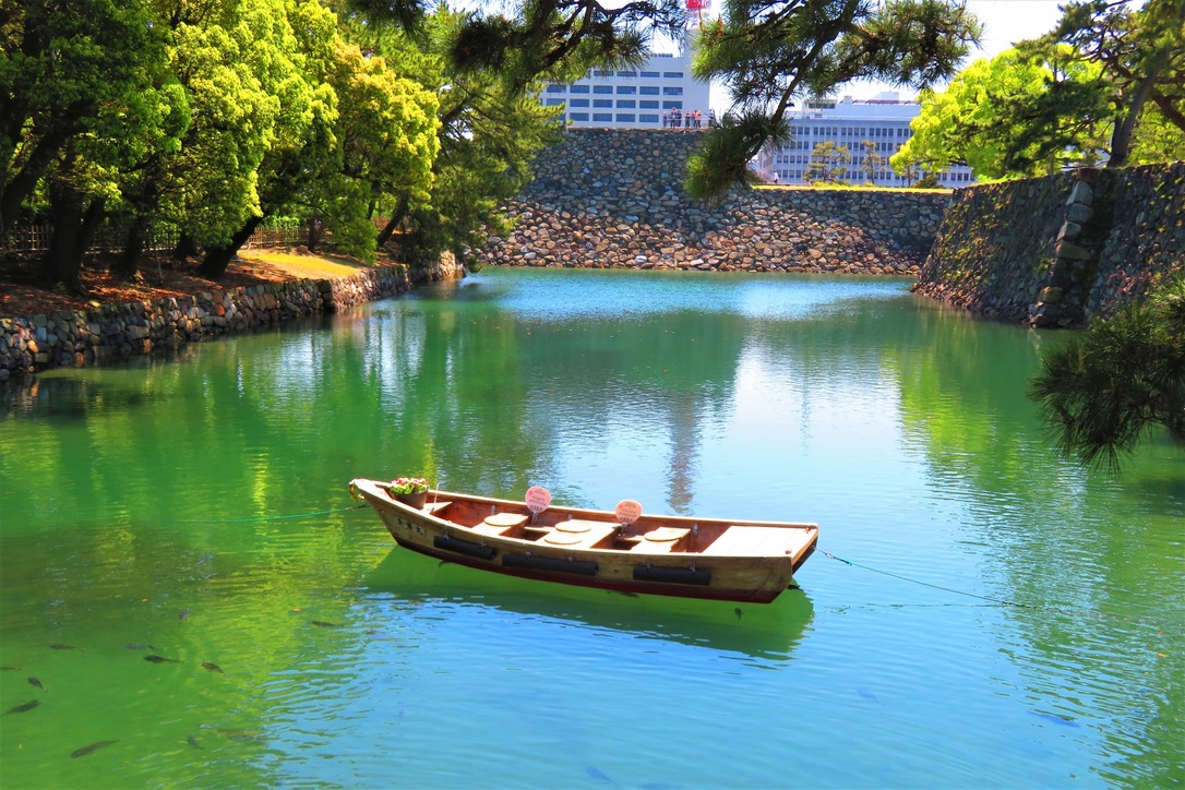 緑に囲まれた高松城の内堀と和船が浮かぶ春の水面 穏やかで風情ある水城の風景