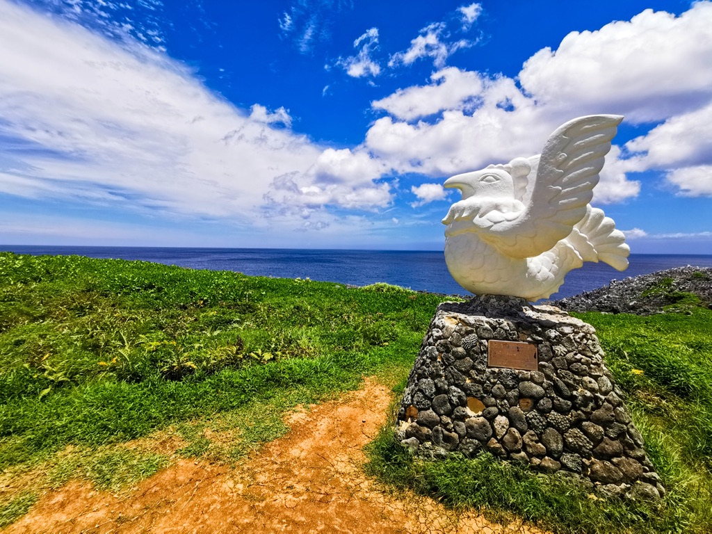 辺戸岬の草原に立つかりゆしの像と広がる海の景色