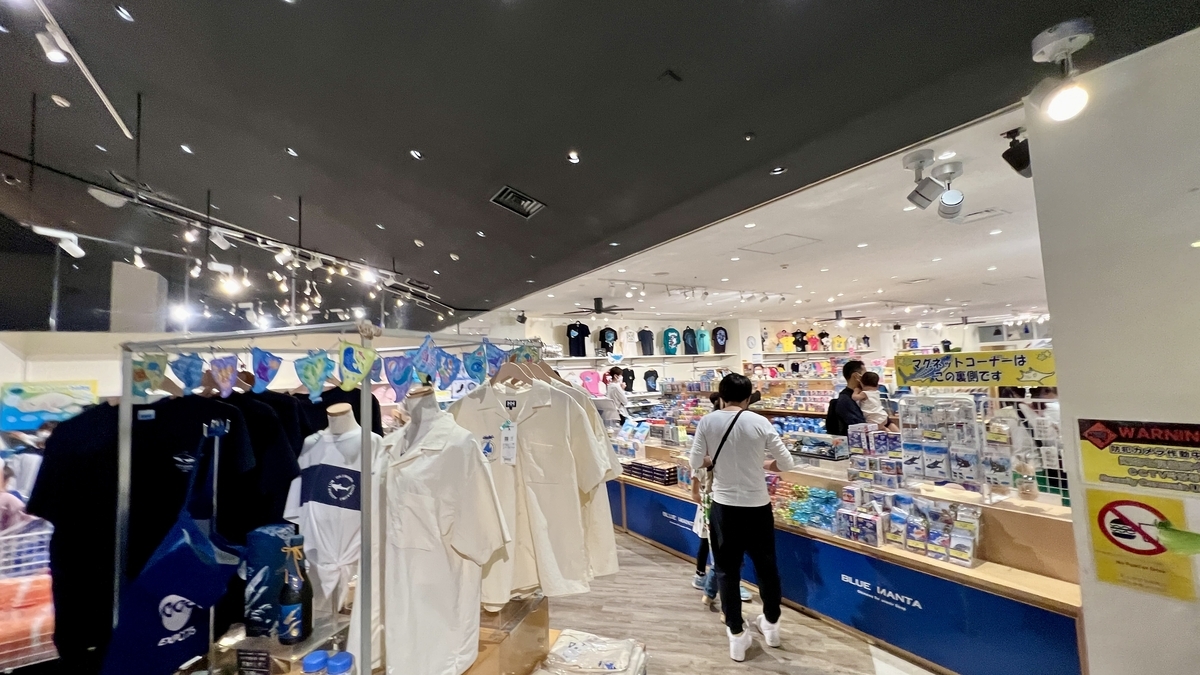 水族館ショップで買い物を楽しむ観光客と商品棚の様子