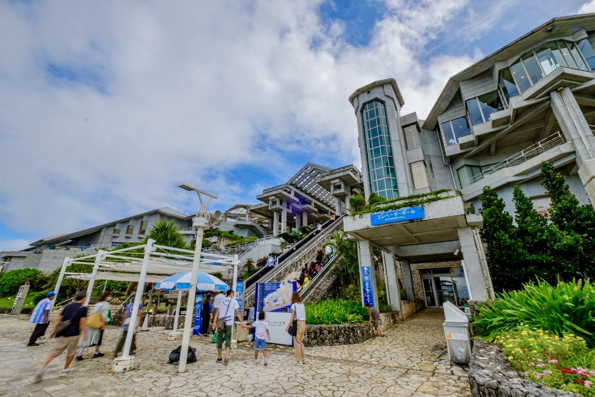 沖縄美ら海水族館の建物外観と入館する観光客の様子