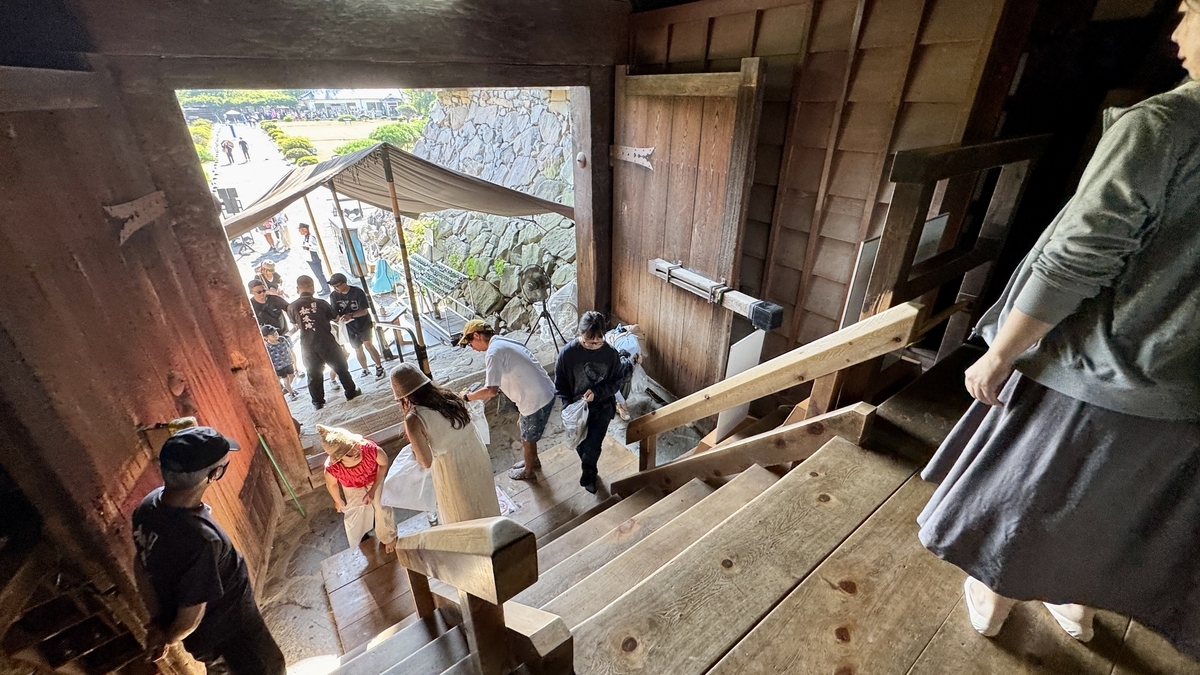 天守入口で靴を脱ぐ観光客と木製の階段