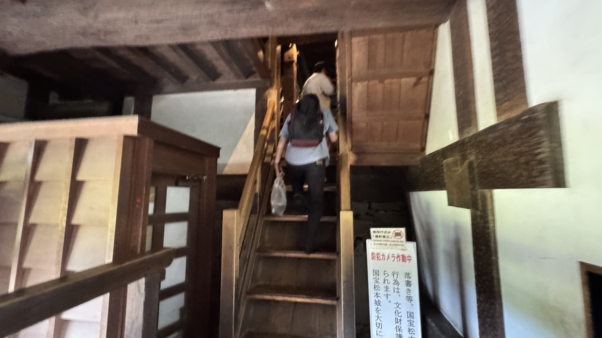 天守内部に続く急な木製階段を上る様子