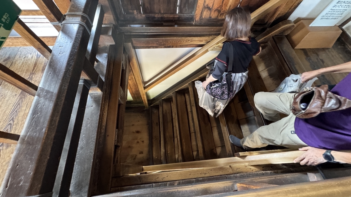 松本城天守出口に続く木製階段を降りる来館者