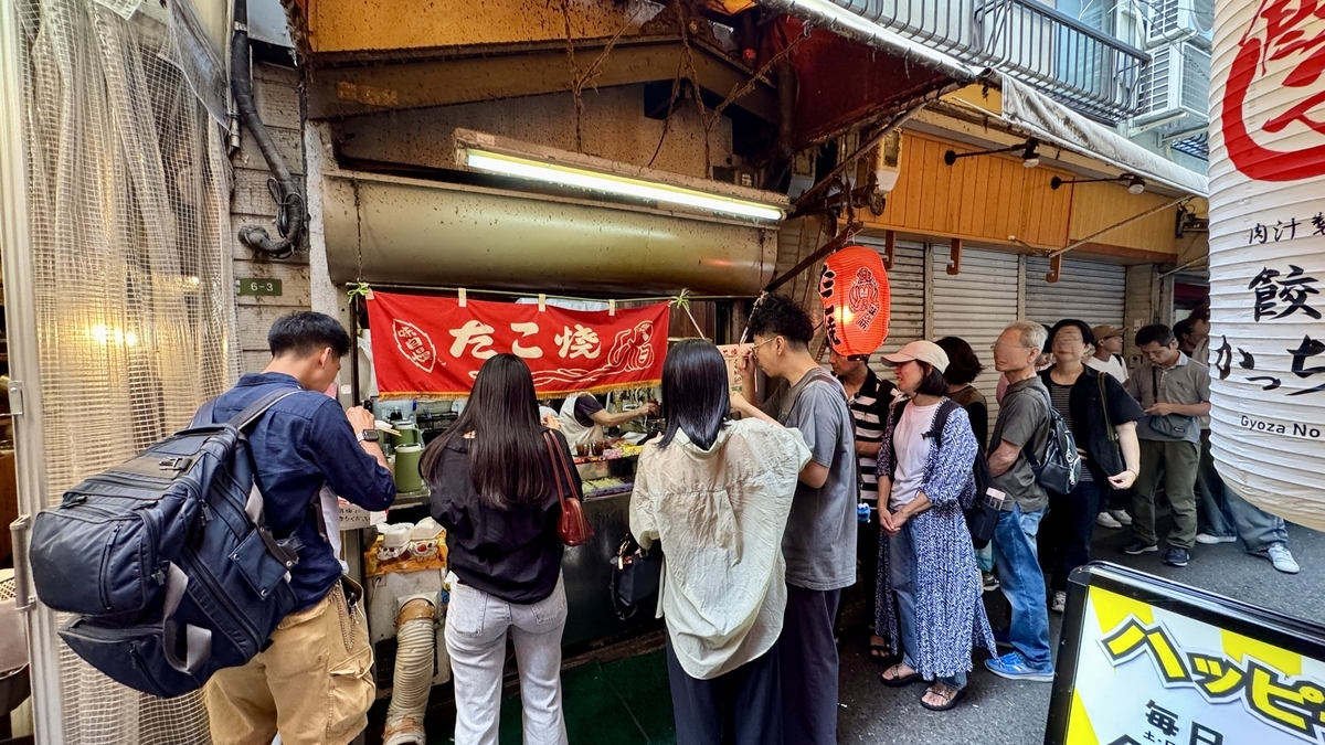 店先に並ぶ人々と赤い暖簾が揺れる寛子の外観