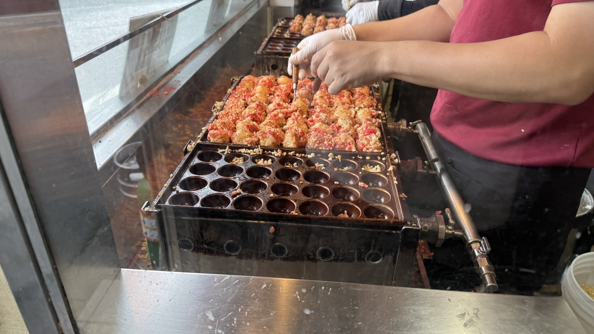 焼き台で職人がたこ焼きを焼いている様子