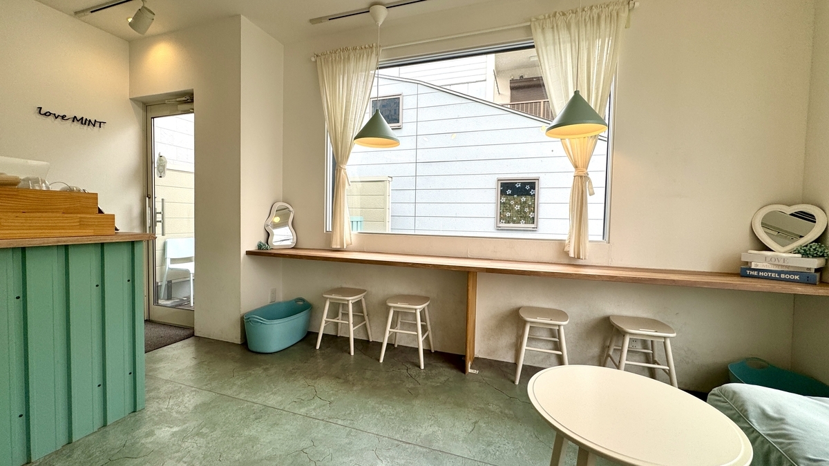 大きな窓とミント色の家具が並ぶ明るい店内の様子