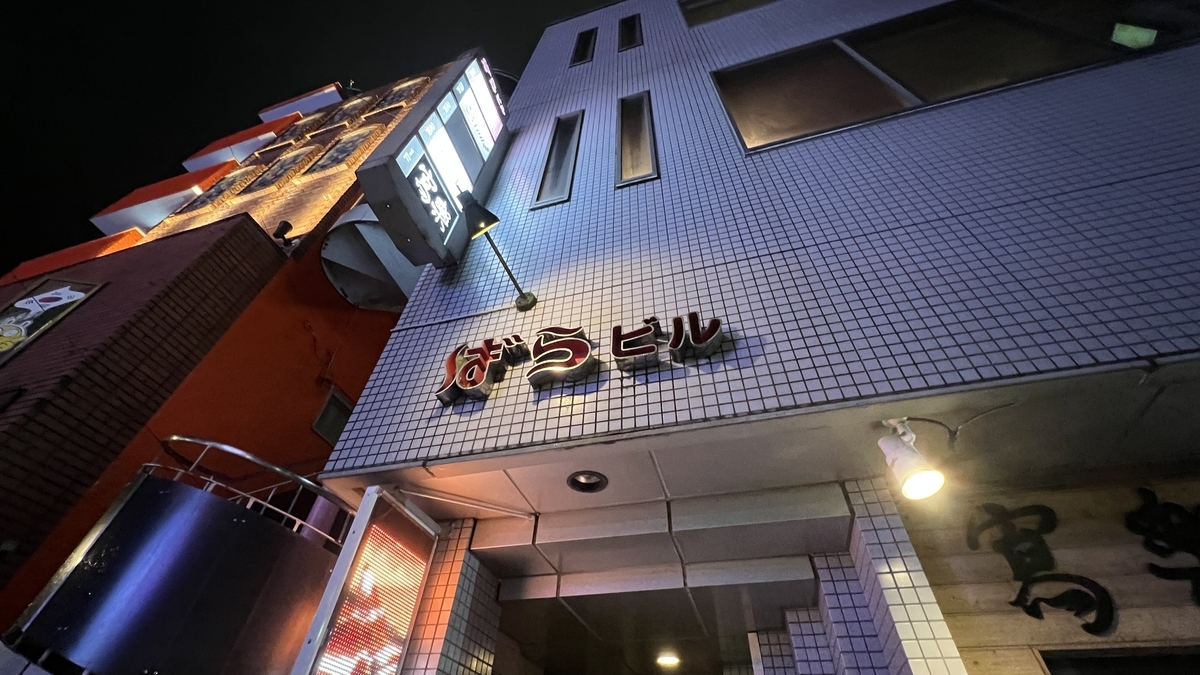 ニシタチにある雑居ビルの外観と夜の看板の明かり