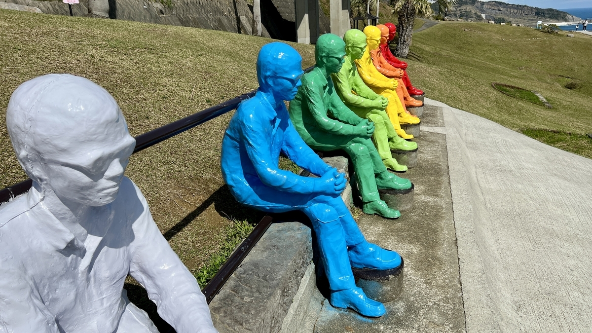 芝生の斜面に向かって配置されたカラフルなヴォワイヤン像の横並び