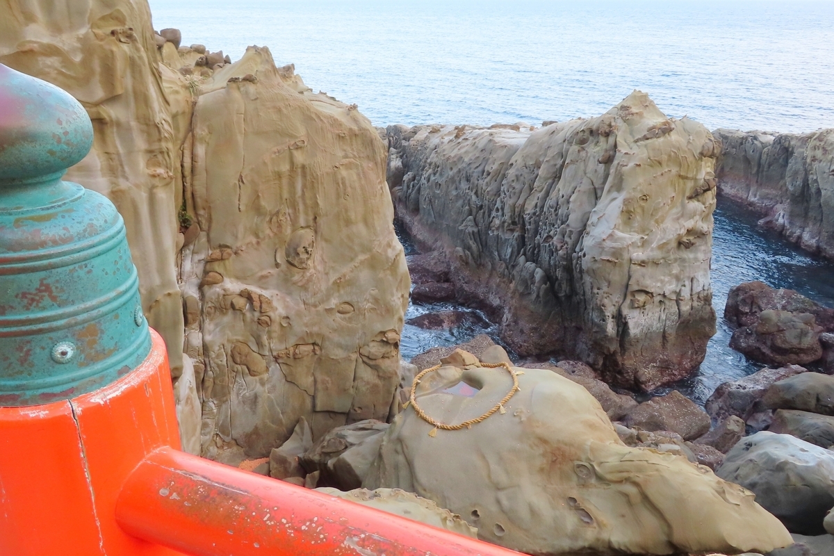 断崖の下にある霊石亀石を参道から望む景観
