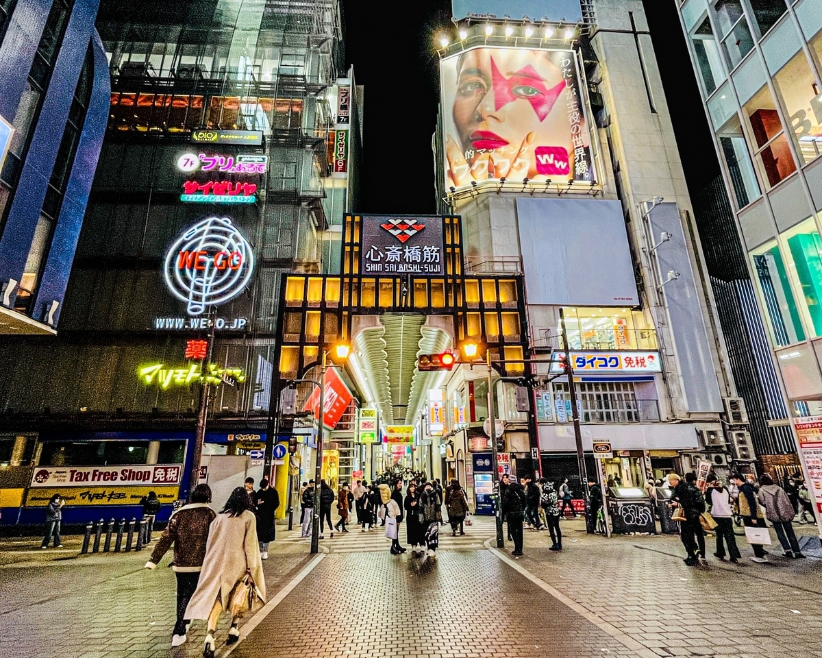 夜の心斎橋の大通りを人々が行き交う華やかな風景