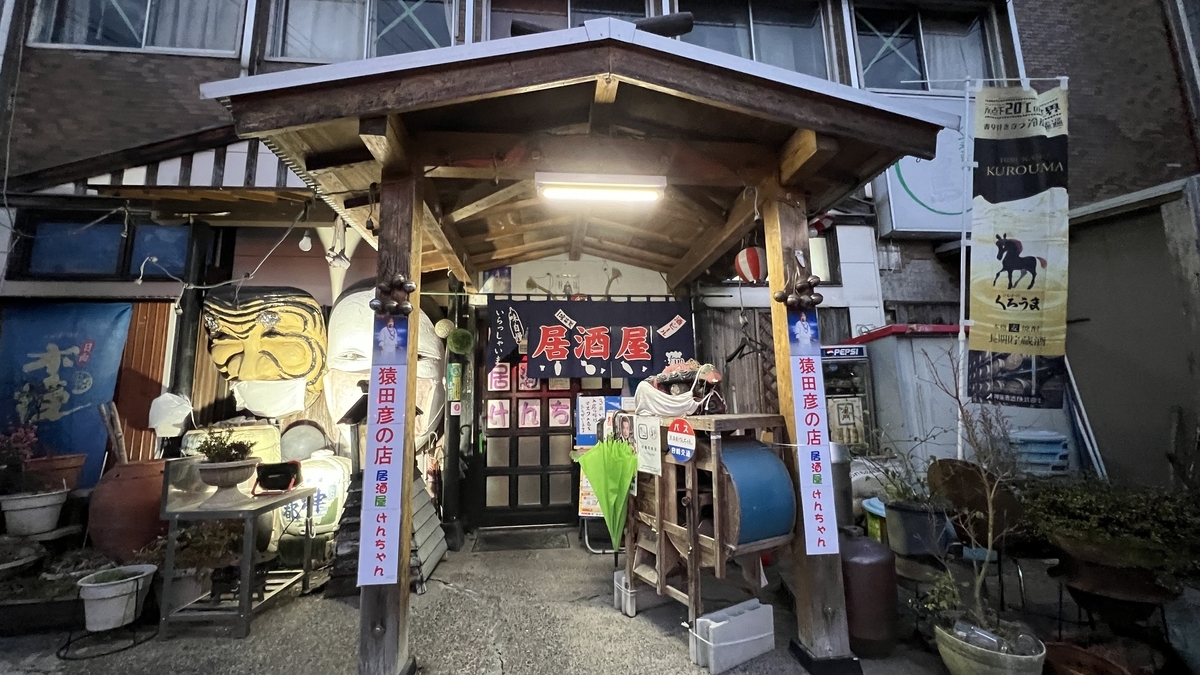 神楽面が掲げられた居酒屋けんちゃんの夜の外観