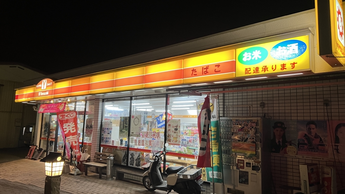 夜に営業するヤマザキYショップ興梠酒米店の外観