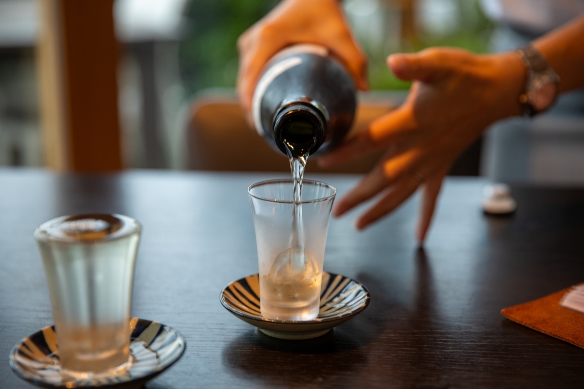 徳利から注がれる地酒と木製カウンターに並ぶお猪口